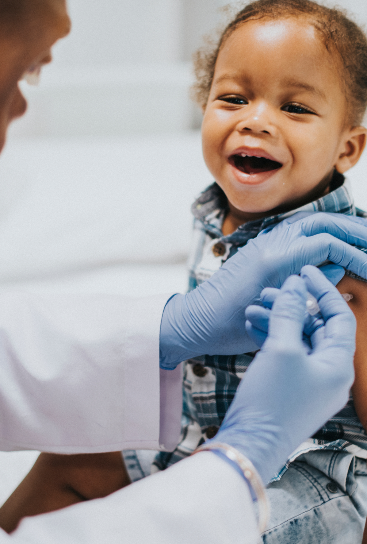 Pediatrician giving a smiling toddler a vaccination
