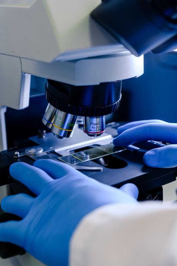 Laboratory scientist examining a sample slide under a microscope
